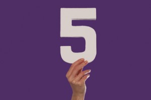 Female hand holding up the number 5