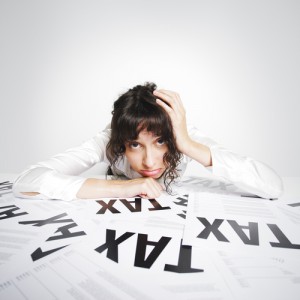 Sad woman on her taxes-paperwork covered desk desperately looking at the camera