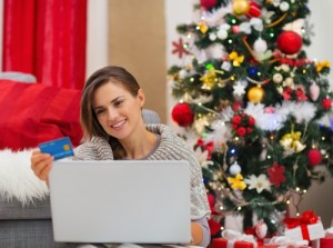 Happy young woman making online purchases near Christmas tree