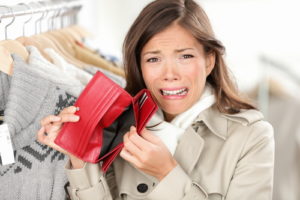 empty wallet - woman with no money in purse shopping. Female shopper in clothes store upset crying as she is out of money. Funny image of mixed race Caucasian / Asian woman.