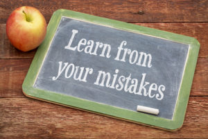 Learn from your mistakes - motivational words on a slate blackboard against red barn wood