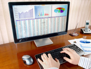 Male hands on the keyboard in front of computer screen with financial data and charts