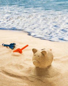 Piggy bank sculpted in sand on sandy beach