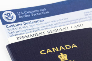 Close up of Canadian passport, permanent resident card, and customs declaration form, some of the paper work required for each entry into the United States.